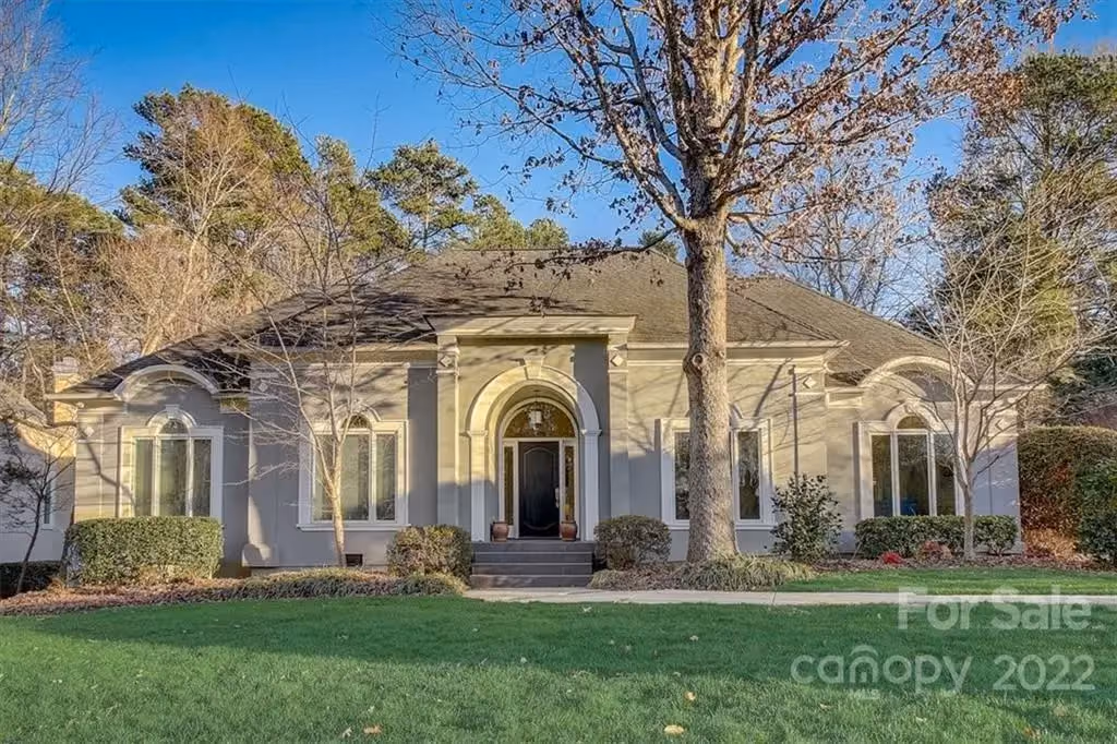 A gray stucco house with arched windows behind a wide lawn, a Davidson home Sunny sold.